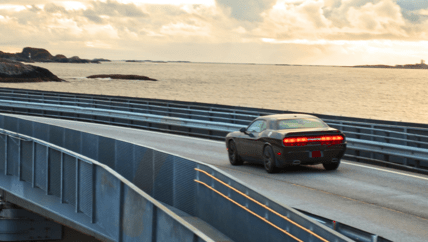 muscle car driving on a bridge over open water