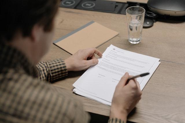 person sitting at table and filling out paperwork