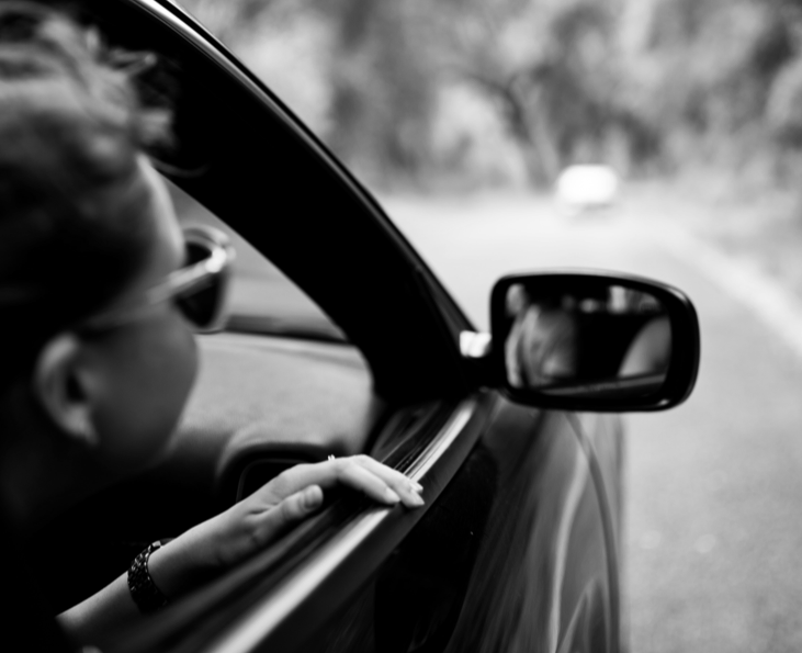 woman wearing sunglasses looking out open car window