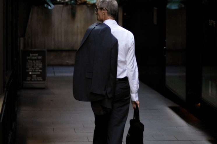 man walking away from camera with blazer draped over his left shoulder