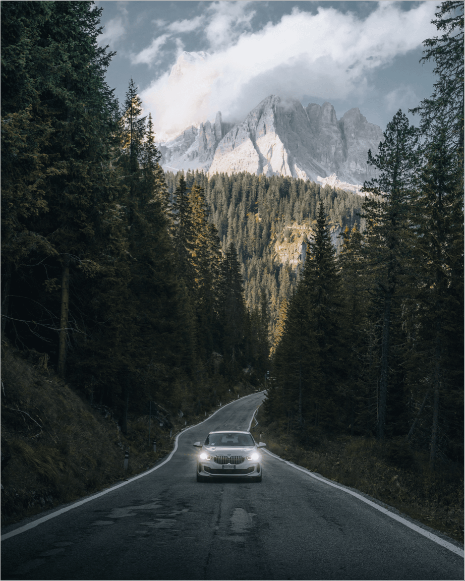 car driving down road between two mountains