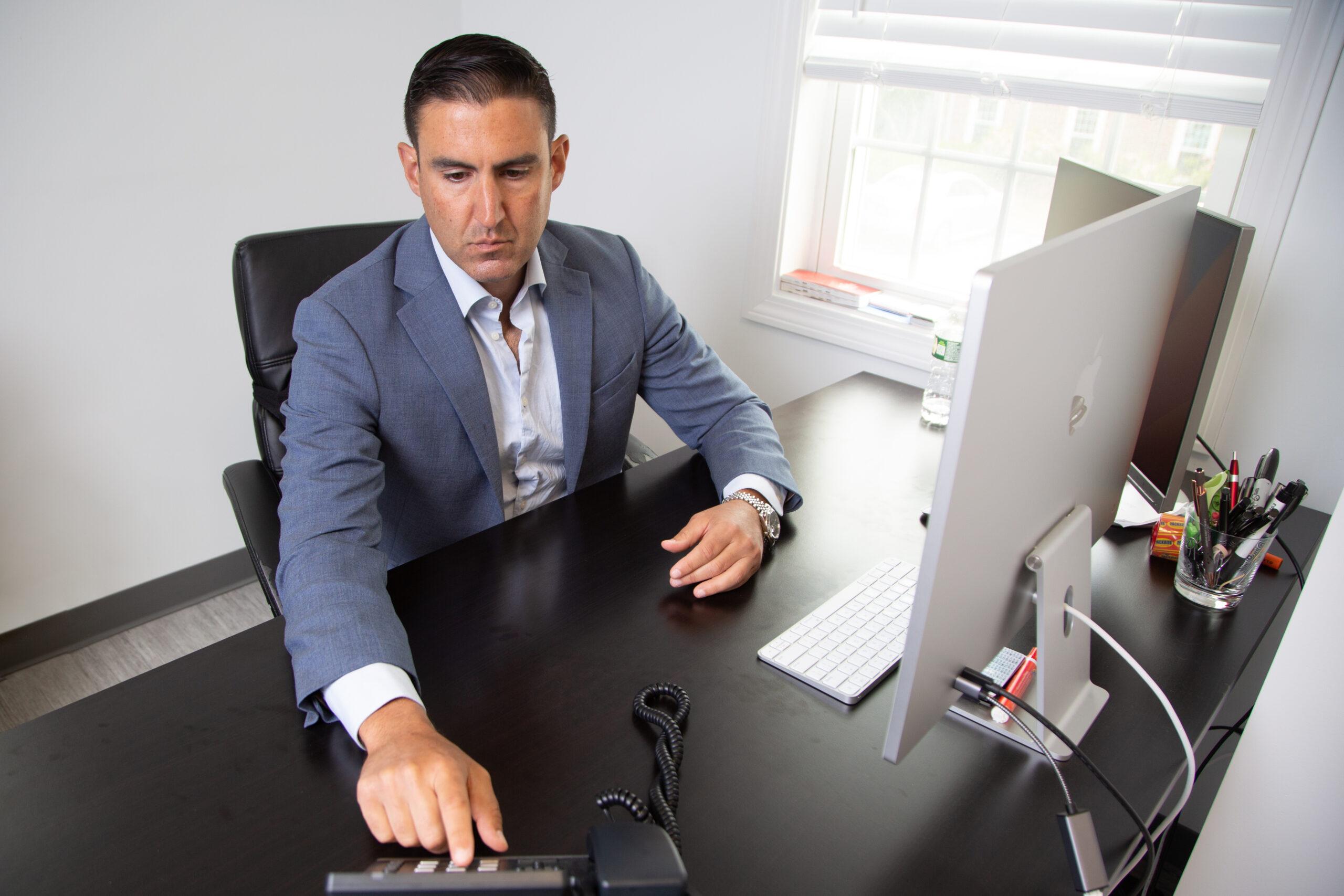 a man in a suit working at his computer desk