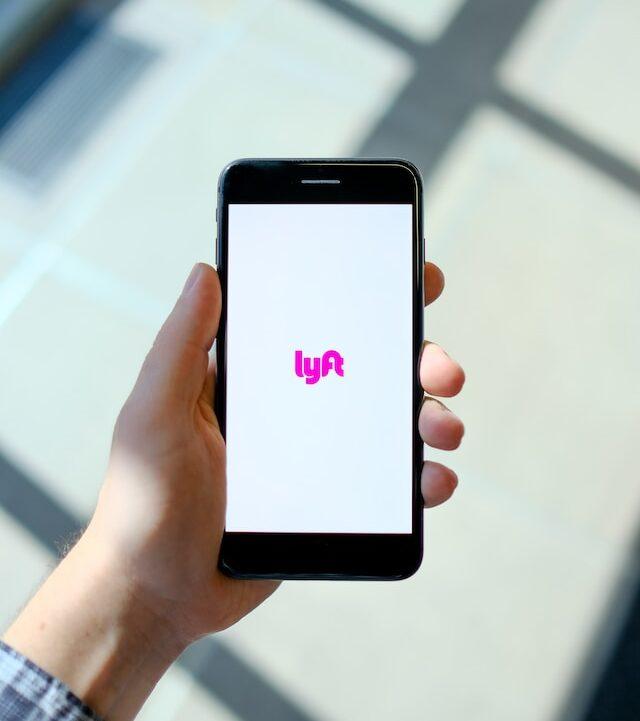 a person holding a cellphone with the Lyft logo on the screen